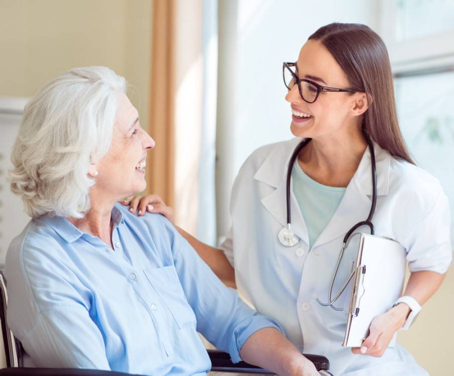 vrouw in rolstoel praat met verpleegkundige